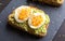Close-up of delicious avocado toast topped with sliced boiled eggs and sesame seeds