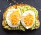 Close-up of delicious avocado toast topped with sliced boiled eggs and sesame seeds