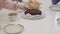Close-up of a delicious chocolate cake at the table. Female Caucasian hands cutting tasty dessert in four pieces. Family