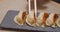 Close-up of delicious fried gyoza on a plate. Hands taking gyoza dumpling with bamboo sticks