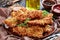 Close-up of delicious grated potato coated and deep fried crispy pork chops on a clay plate on a rustic wooden table with brown