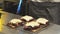 Close-up of a delicious sandwiches with pastrami, pickles and cheese on the table. Male chef melting cheese with a gas burner