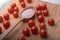 Close-up of delicious small red cherry tomatoes around a large wooden spoon with coarse pink salt, on a natural wooden surface.