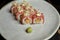 Close up of delicious sushi roll set decorated with sprouts served on white plate with wasabi on black background