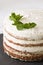 Close-up of delicious white cream icing cake with mint leaves served on the black board. Homemade naked cake with cream, decorated