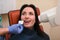 Close up of dentist putting intraoral shield to female patient mouth and assistant directing x-ray