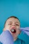 Close up of dentist`s hands with assistant in blue gloves are treating teeth to a child, patient`s face is closed