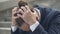 Close-up of depressed man in Covid-19 face mask holding head with hands and thinking. Portrait of stressed Caucasian