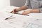 Close up detail of beautiful young female architect in striped shirt sitting at desk, holding pen and ruler in hands