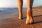 Close up detail bottom behind pov view of pretty female person barefoot legs heel walking by scenic sandy ocean or sea