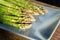 Close-up detail bunch of fresh raw green asparagus plant harvested at season on blue cerami plate kitchen background