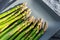 Close-up detail bunch of fresh raw green asparagus plant harvested at season on blue cerami plate kitchen background