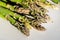 Close-up detail bunch of fresh raw green asparagus plant harvested at season on blue rustic fabric kitchen background