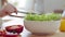 Close-up detail, cropped shooting female hands unrecognizable teen girl in apron cooks salad puts green lettuce leaves