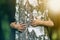 Close-up detail of isolated growing big strong tree trunk embraced from behind by small white child hands on blurred background.