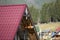 Close-up detail of new modern house top with shingled red roof and wooden sidings on foggy spruce mountains background.