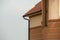 Close-up detail side stucco wall of big modern expensive residential family cottage with gutter rain pipe system on blue sky