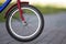 Close-up detail of teenager bicycle front wheel on gray pavement blurred bokeh background on bright sunny day. Urban comfortable t