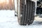 Close-up detail view of car wheel with unsafe summer tread tire during driving through slippery snow road at winter