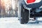 Close-up detail view of car wheel with unsafe summer tread tire during driving through slippery snow road at winter