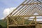 Close-up detail of wooden high steep roof framing under construction. Timber frame of natural materials against bright sky.