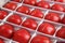 Close up detailed corner view background wallpaper shot of rows and lines of large tasty red ripe tomatoes in a white crate box