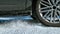 CLOSE UP: Detailed shot of car\\\'s spinning wheels as it slides along snowy road.