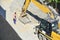 Close up details of an industrial excavator working on a construction site. Excavator bucket levels gravel on the roadway. Men at