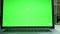 Close-up device on white table, green screen on the laptop, inside modern empty office