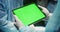 Close-up of a digital tablet with a green screen in the hands of a doctor