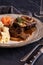 Close up a dinner plate of braised short ribs with mashed potatoes and baby carrots ready for eating.