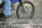 Close up of a dirt bike and rider in a mud puddle.