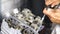 Close up of disassembled motorcycle engine. Professional mechanic repairing motor using tool. Repairer working in garage