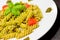 Close-up of dish of pasta with pesto genovese sauce and vegetables, tomato and basil