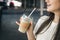 Close-up, disposable cup of iced coffee in female hands.