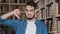 Close-up dissatisfied upset indian man student looking at camera standing in library showing thumb down demonstrating