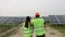 Close up of diverse engineers in special uniform walking through solar farm. The rows of solar batteries. Green energy