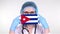 Close-up. Doctor in glasses, blue medical cap, gloves holds in hands medical mask with Cuba flag. Physicians care