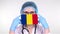 Close-up. Doctor in glasses, blue medical cap, gloves holds in hands medical mask with Romania flag. Physicians care