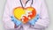 Close-up. Doctor in medical white coat, blue gloves holds in hands drawn pulsating heart with Bhutan flag. Concept of