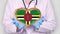 Close-up. Doctor in medical white coat, blue gloves holds in hands drawn pulsating heart with Dominica flag. Concept of