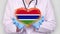Close-up. Doctor in medical white coat, blue gloves holds in hands drawn pulsating heart with Gambia flag. Concept of