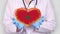 Close-up. Doctor in medical white coat, blue gloves holds in hands drawn pulsating heart with Morocco flag. Concept of