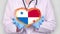 Close-up. Doctor in medical white coat, blue gloves holds in hands drawn pulsating heart with Panama flag. Concept of