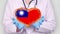 Close-up. Doctor in medical white coat, blue gloves holds in hands drawn pulsating heart with Taiwan flag. Concept of