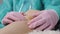 Close-up of the doctor's hands in medical gloves, who examines the injured knee of a female patient.