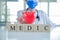 Close-up doctor in uniform wearing a face mask with a stethoscope and hold red heart with wood cubes word MEDIC