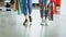 Close-up dolly shot of women`s legs walking slowly through luxurious shop. Women are wearing jeans and trainers and