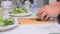 Close up and dolly slider shot woman hand cutting green vegetable on white table HD 1920x1080