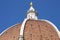 Close-up dome of the Cathedral of Florence Santa Maria del Fiore against a blue sky. On the observation deck are tourists